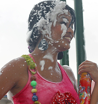 Young woman holding foam spray can with her face partially covered in foam at the Barranquilla Carnival