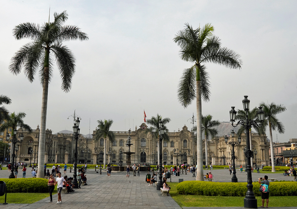 Government Palace of Lima, Peru Peruvian Government Palace in Plaza Mayor, Lima with palm trees, flags, and people in the square