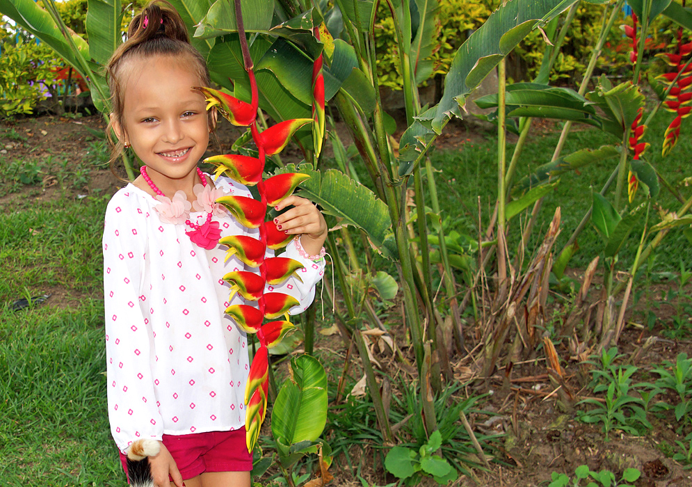 Beautiful young girl holding onto a colorful Heliconia rostrata inflorescence