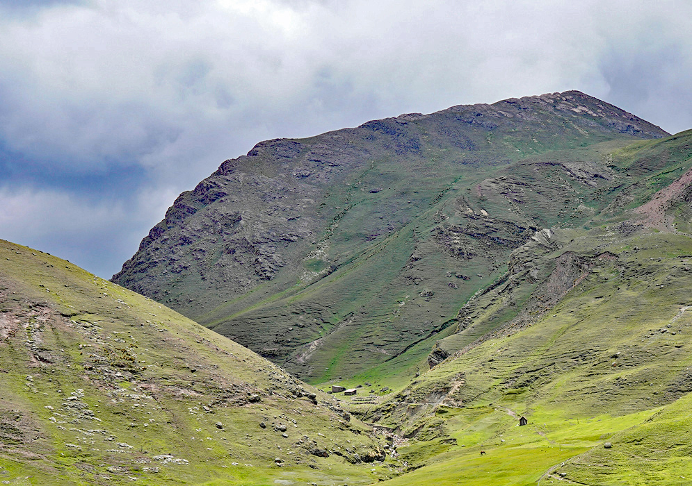 Huts in Cusco Region Scattered traditional huts and stone trails set against the rugged, green mountains of the Cusco highlands