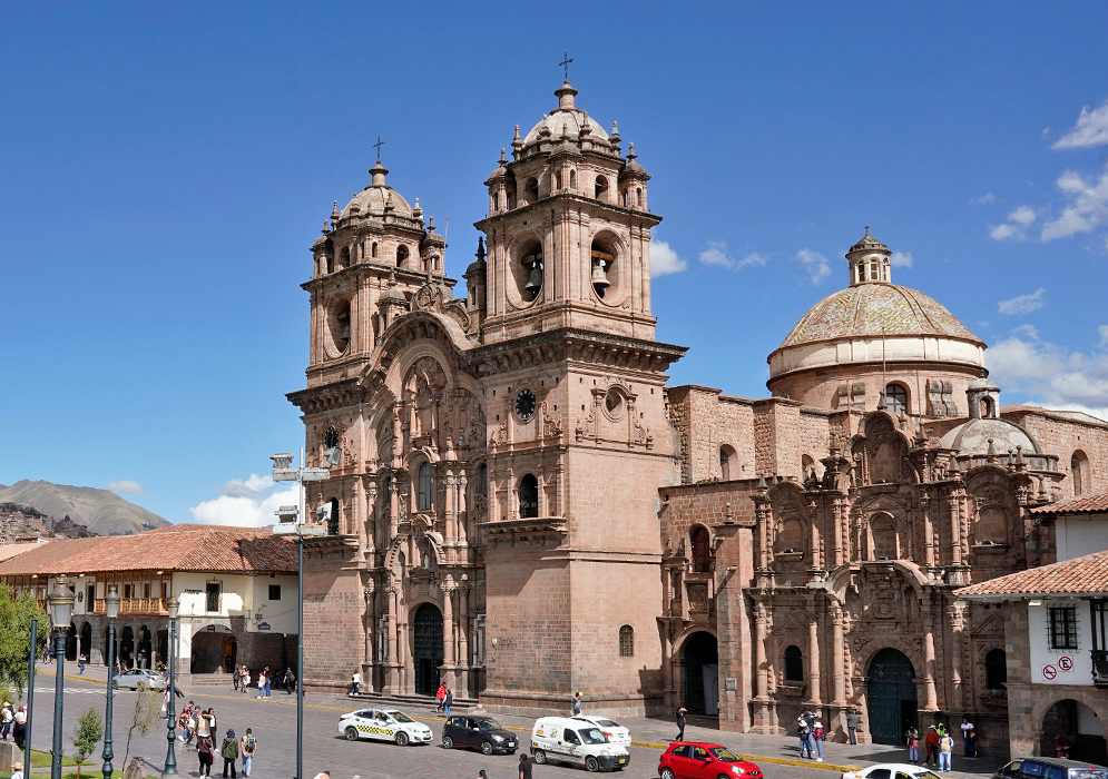 Side View of Compañía de Jesús Church from the Plaza Angled view of Iglesia de la Compañía de Jesús and its domed roof facing the busy stone-paved Plaza de Armas with taxis and tourists nearby