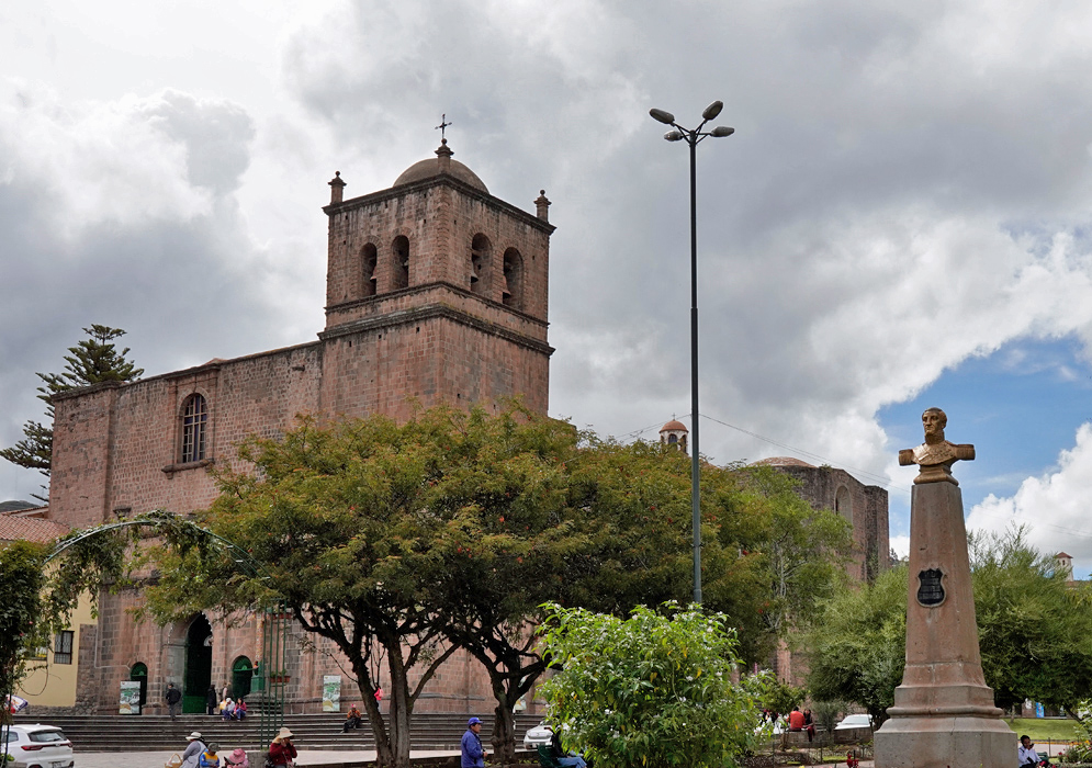 Church of San Francisco de Asís Cusco Iglesia San Francisco de Asís in Cusco seen behind a statue and trees, with its tall bell tower and simple stone walls