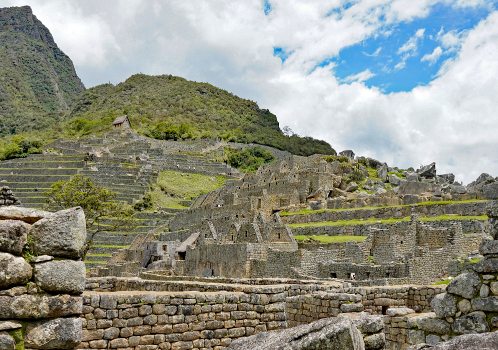 Inca Ruins Machu Picchu Overview of layered stone walls and terraces of the Machu Picchu ruins stretching up the green Andean slope