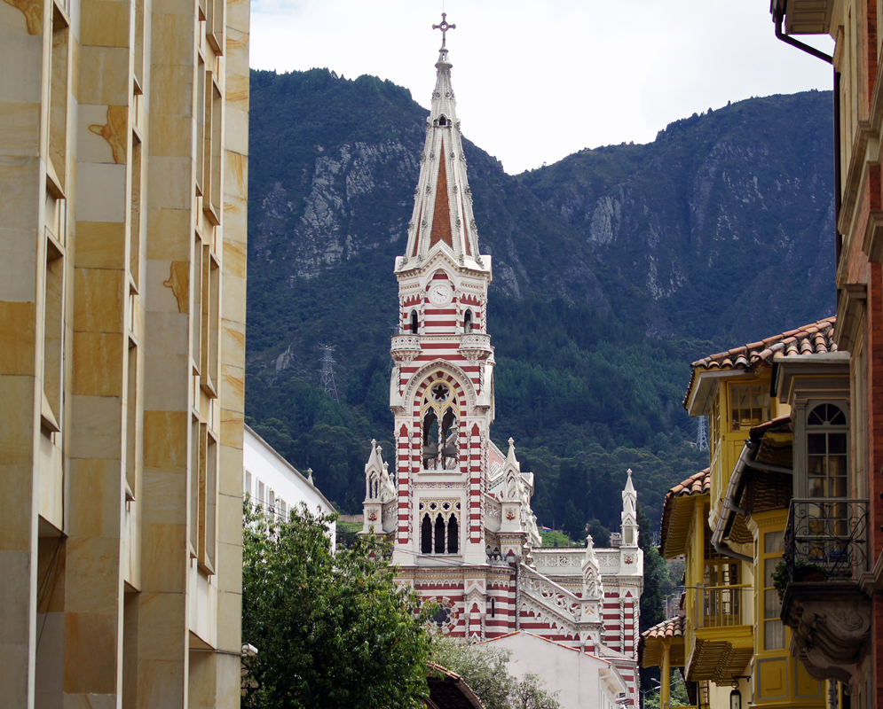 Red and white church steeple against a mountain backdrop