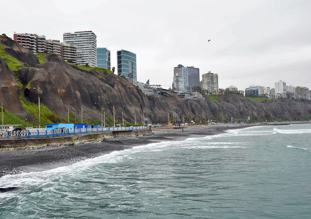 Lima’s Pacific Ocean Coast with Skyline in the Distance Rocky Pacific coastline in Lima with crashing waves and a panoramic view of the distant city skyline