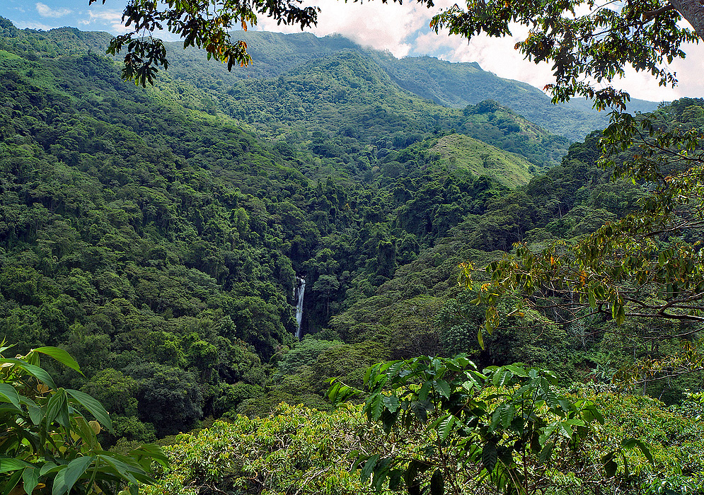 Waterfall from the distance surrounded by green mountains
