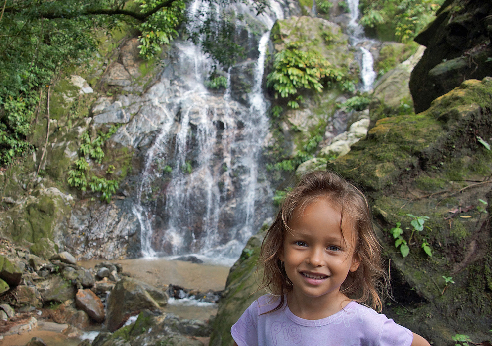 Four year old girl standing in front of waterfall