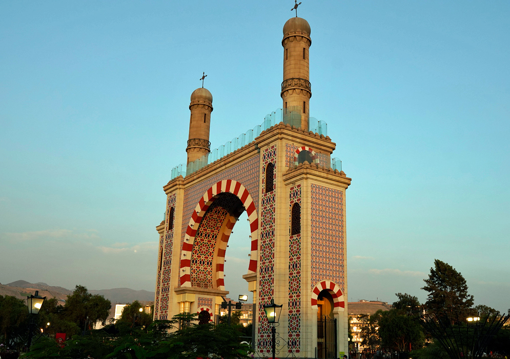 Moorish Arch of Miraflores Moorish Arch of Miraflores at sunset with its red-and-white striped archway and two ornate towers, surrounded by trees and distant mountains