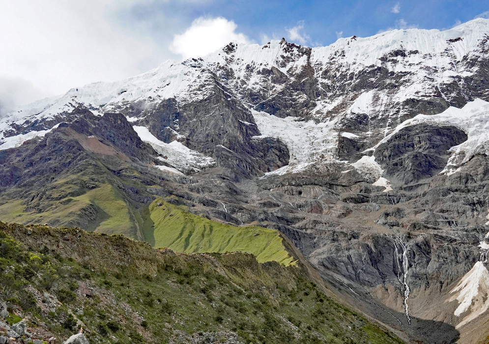 Humantay peak cloaked in glacial ice and swirling clouds, viewed from a nearby thatched-roof Humantay peak cloaked in glacial ice and swirling clouds, viewed from a nearby thatched-roof