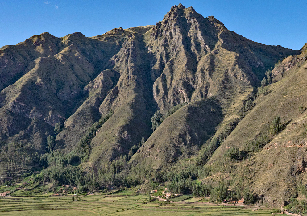 Scenic panorama of Ollantaytambo’s archaeological ruins and town surrounded by rugged Andean peaks and terraced slopes under a clear sky