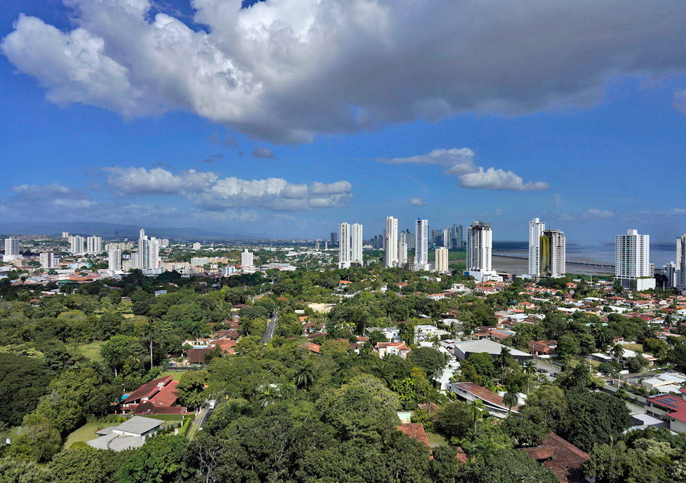 Urban and Coastal Panama City Wide cityscape showing a mix of residential neighborhoods and tall buildings with lush greenery and distant skyscrapers along the Pacific coast
