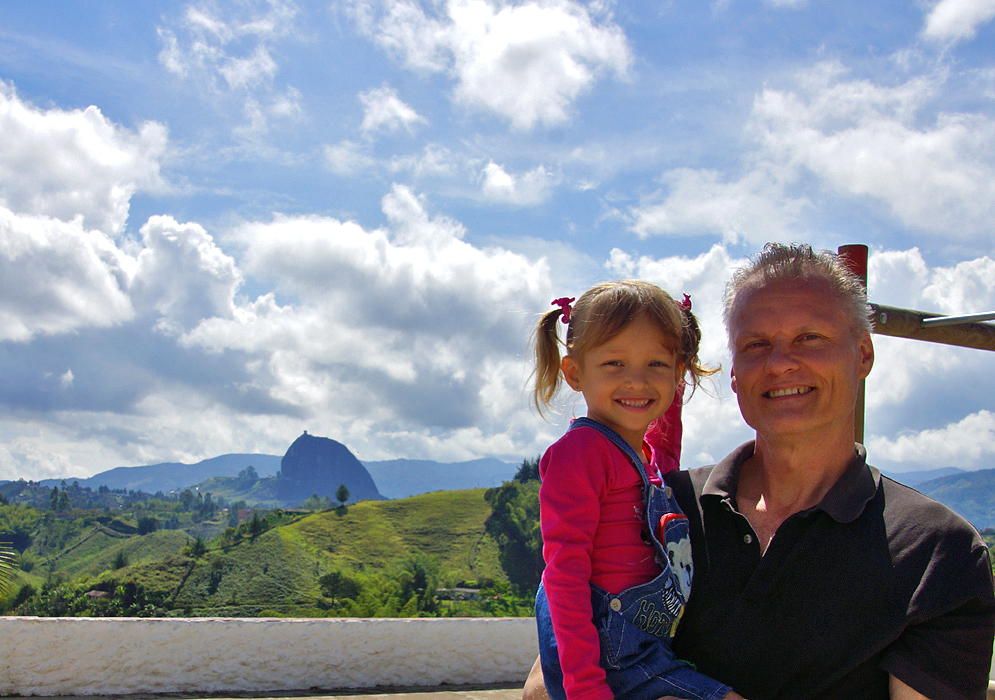 Father holding smiling four year old daughter with El Penon in the background