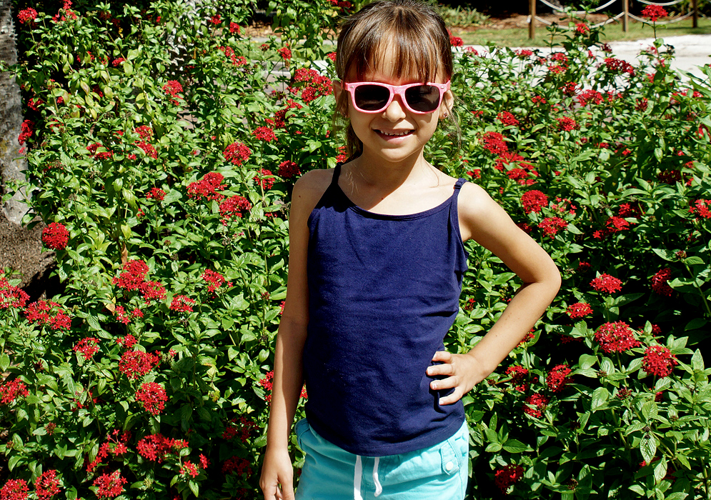 Pretty girl standing in front of a Pentas lanceolata bush with red flowers