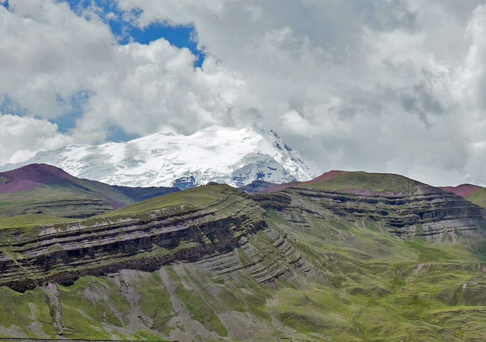 Peruvian Andes Snowy Peaks A dramatic contrast of deep green valleys and snow-covered summits in the Peruvian Andes, with striped layers of red and purple sediment visible in the slopes