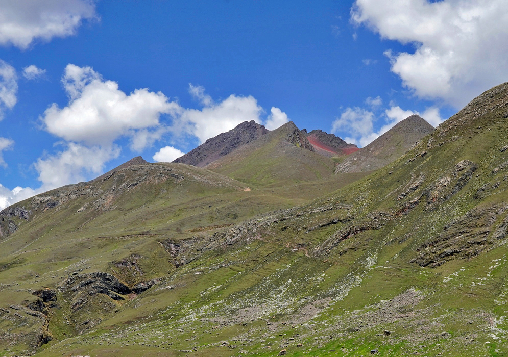 Vilcanota Highlands and Ridges Rolling hills and sharp ridges in the Vilcanota range with patches of páramo vegetation and exposed rock under a partly cloudy sky
