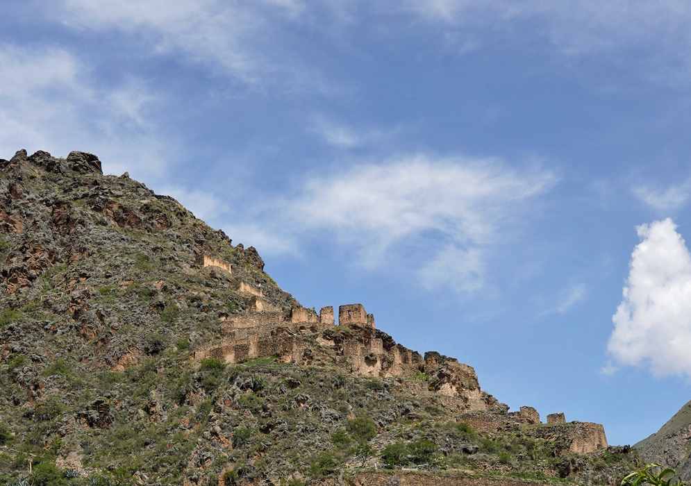 Pinkuylluna Granary Hillside Ancient Inca stone storage buildings scattered across a hillside at Pinkuylluna, rising along the rocky terrain beneath a wide sky