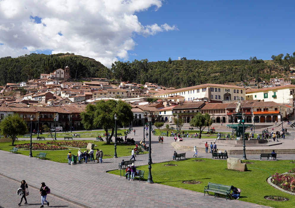 Plaza de Armas, Cusco with hillside view Plaza de Armas in Cusco filled with visitors and surrounded by colonial buildings and hills with a blue sky overhead