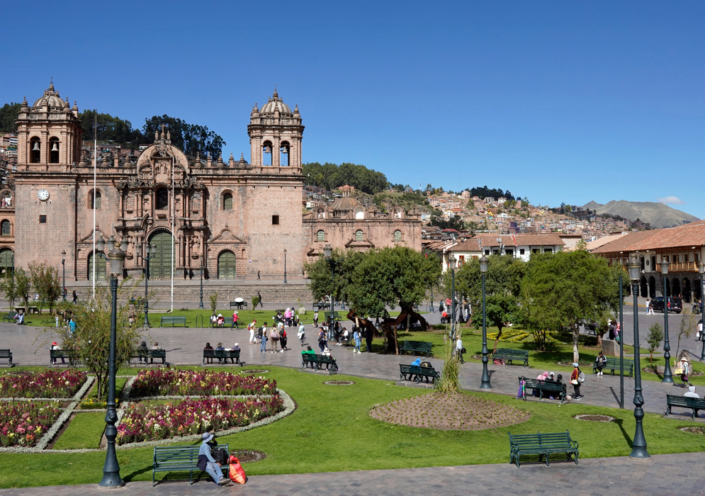 Plaza de Armas View Peru Green lawns, flower beds, and surrounding architecture in Cusco’s Plaza de Armas with the cathedral and city hills in the background