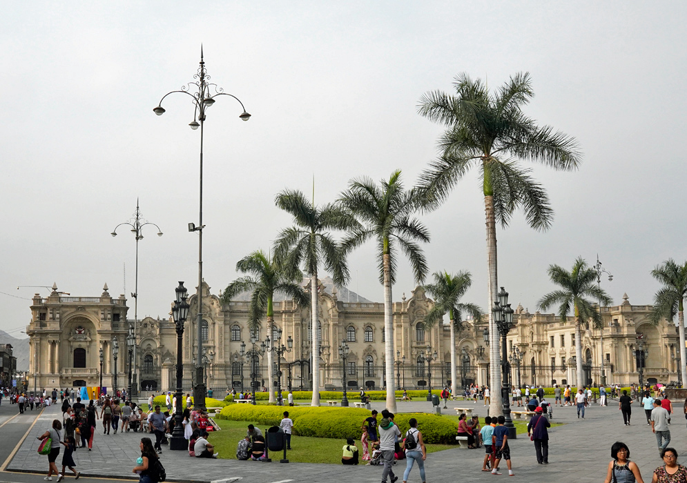 Plaza Mayor de Lima Peru Tourists and locals gather in the historic Plaza Mayor of Lima, featuring colonial facades, palm trees, and scenic views of the presidential palace