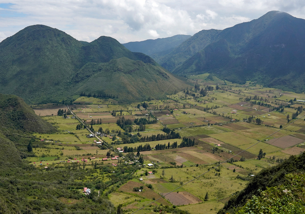 Pululahua Crater Farmland Ecuador Aerial view of the Pululahua Crater in Ecuador, showcasing lush farmland and scattered homes nestled within the green volcanic caldera surrounded by steep forested mountains