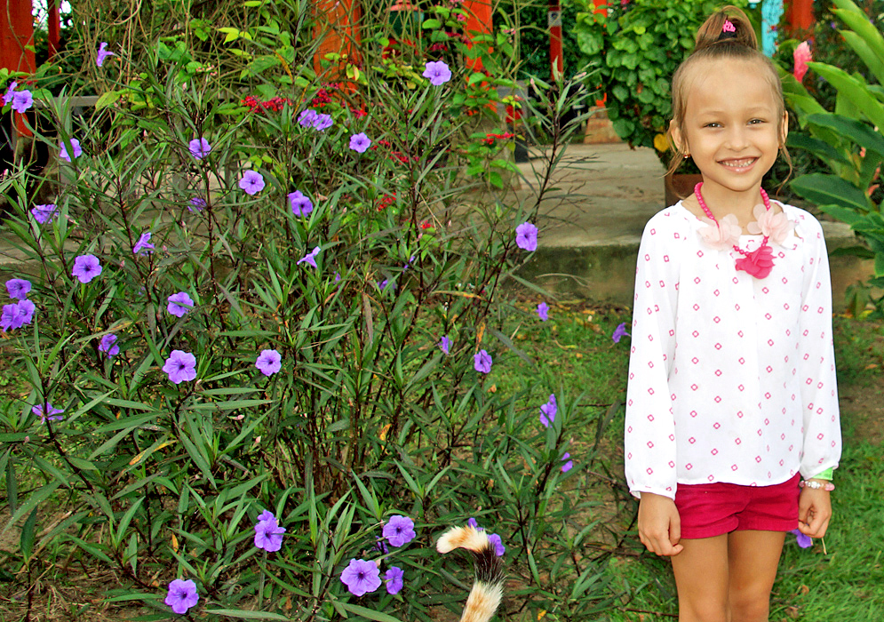 Smiling attractive girl next to purple Ruellia brittoniana flowers