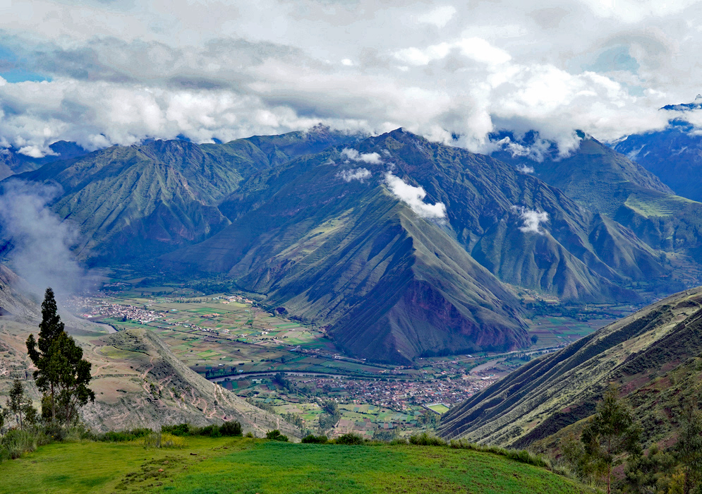 Agricultural fields, rural homes, and distant Andean peaks seen from above in a fertile section of the Sacred Valley in Peru