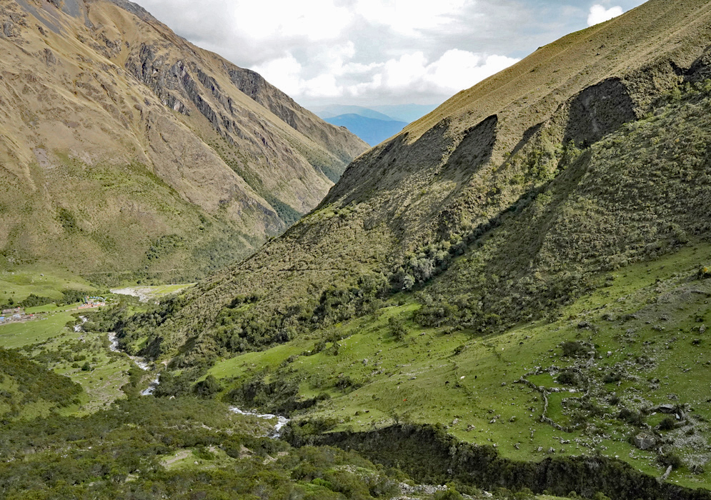 Salkantay Valley Landscape A wide green valley with sloping mountainsides and a winding river in the Salkantay region of Peru, leading toward distant hazy mountain ranges on the horizon