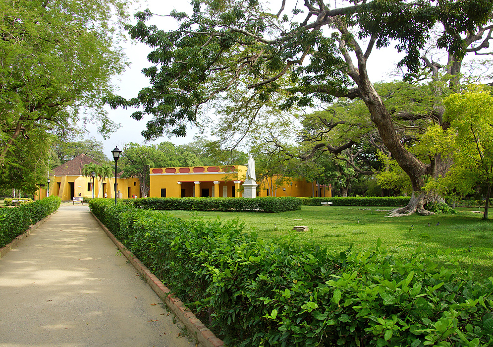 A walkway leading to yellow buildings and a statue