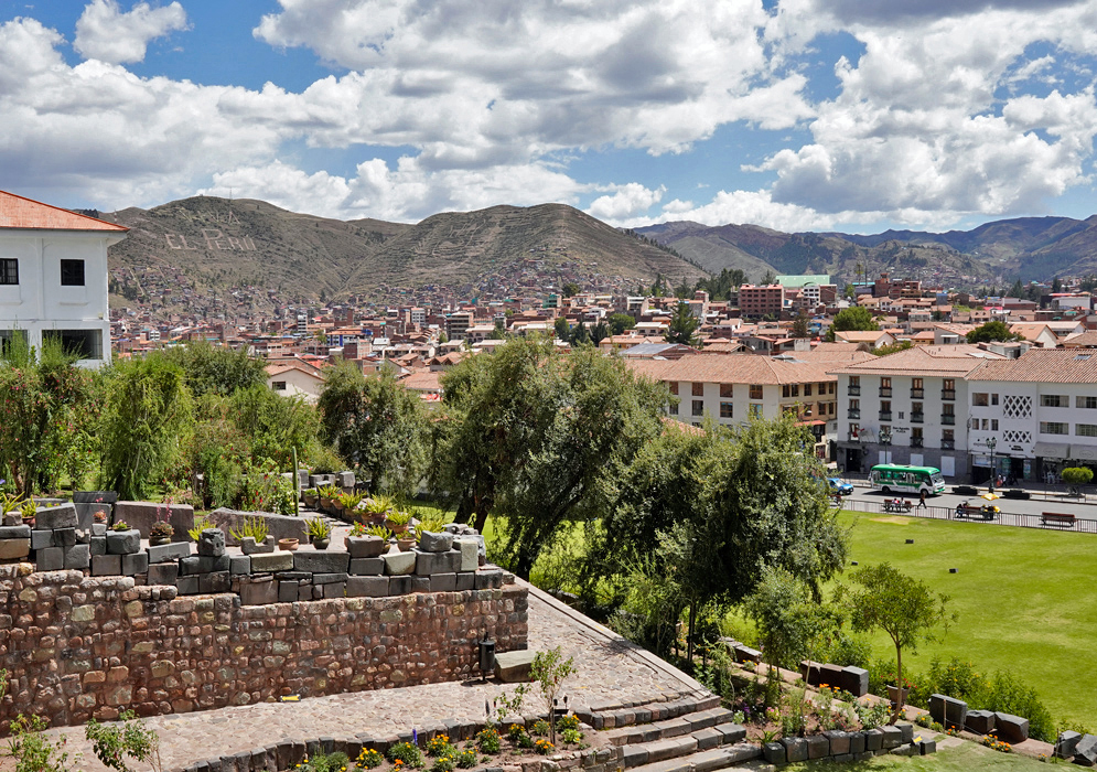 Sunny Day Overlooking Cusco, Peru Panoramic view of Cusco, Peru on a sunny day, with red-tiled roofs, colonial buildings, and green mountains in the background
