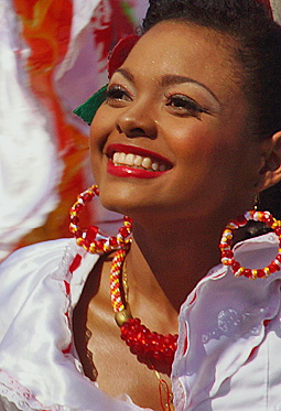 Radiant Colombian Woman at Barranquilla Carnival Joyful woman in traditional white attire with red jewelry and festive earrings, beaming under the sun during the Barranquilla Carnival parade