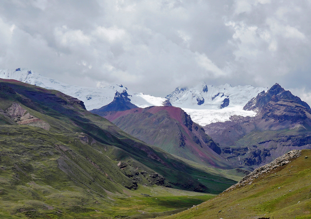 Vilcanota Mountain Range Remote stretch of the Vilcanota mountain range with rolling grassy hills and distant jagged summits capped in clouds