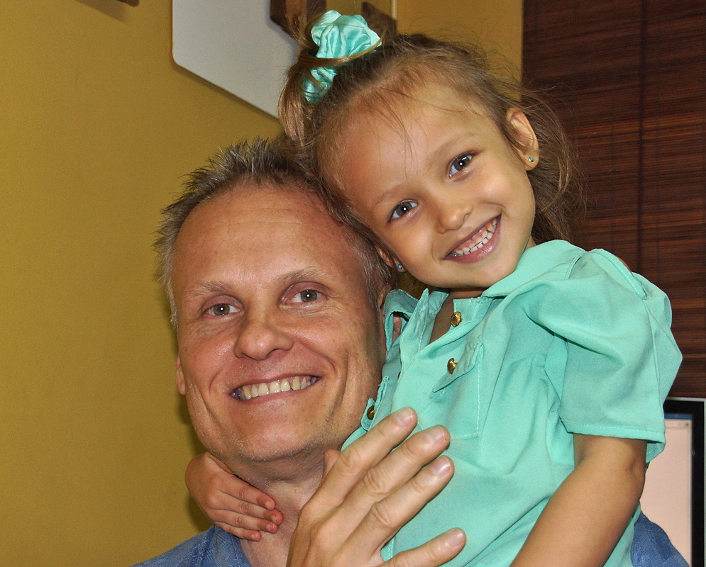 Danica Alejandra Morrow Daza laughing and hugging her dad, with her arms around him, while he smiles back