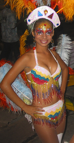 Young carnival dancer in a colorful fringed costume and decorative makeup smiling during nighttime festivities in Barranquilla