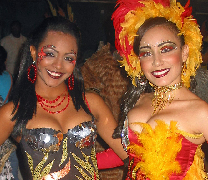 Two smiling Caribbean women in bold and colorful carnival costumes posing during Barranquilla Carnival night festivities